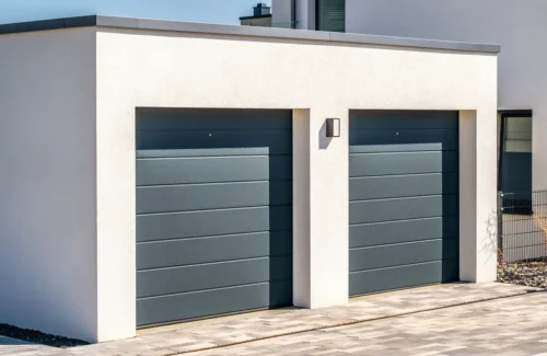 Einzelgarage mit grauem Sektionaltor als Anbau an ein Einfamilienhaus